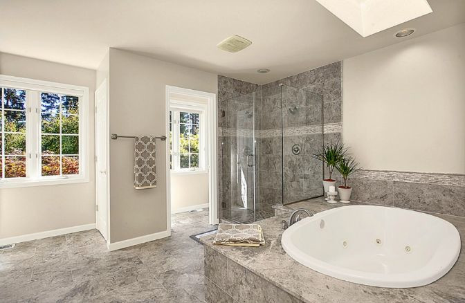 Exemple d'une salle de bain chic avec un placard avec porte à panneau surélevé, des portes de placard blanches, un plan de toilette en marbre, une baignoire posée, un carrelage gris, un carrelage de pierre, un mur gris et un sol en marbre.