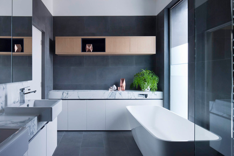 Diseño de cuarto de baño principal contemporáneo con armarios con paneles lisos, puertas de armario blancas, bañera exenta, baldosas y/o azulejos grises, lavabo sobreencimera, suelo gris y encimeras blancas