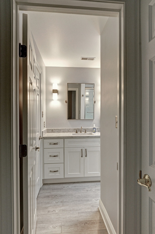 Bathroom - mid-sized transitional kids' white tile and porcelain tile porcelain tile and gray floor bathroom idea in Philadelphia with shaker cabinets, a two-piece toilet, an undermount sink, quartz countertops, beige countertops, white cabinets and gray walls