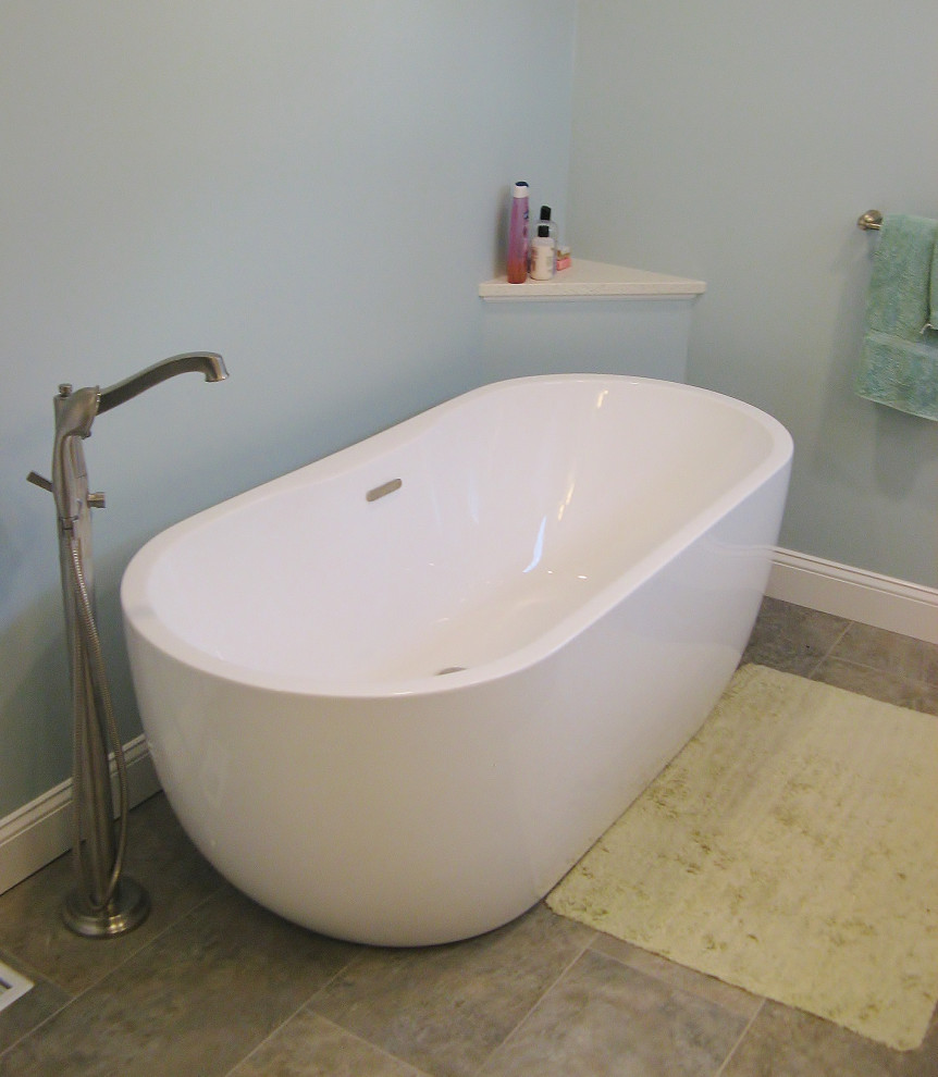 Photo of a large traditional ensuite bathroom in Philadelphia with recessed-panel cabinets, white cabinets, a freestanding bath, a corner shower, a one-piece toilet, blue tiles, blue walls, laminate floors, a submerged sink, engineered stone worktops, beige floors, a hinged door and white worktops.