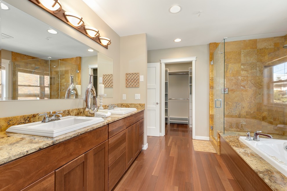 Esempio di una grande stanza da bagno padronale american style con vasca da incasso, pareti gialle, parquet scuro, lavabo da incasso, pavimento marrone, porta doccia a battente e top giallo