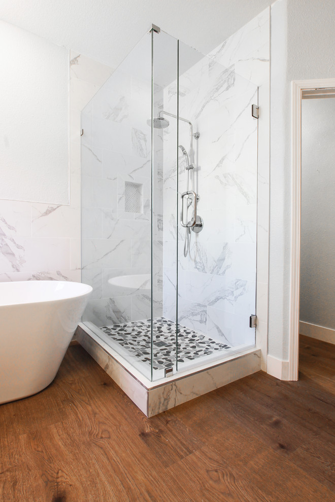 Large modern ensuite bathroom in Sacramento with shaker cabinets, white cabinets, a freestanding bath, a corner shower, white tiles, marble tiles, white walls, medium hardwood flooring, a submerged sink, brown floors, a hinged door and white worktops.