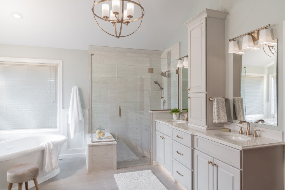Large traditional ensuite bathroom in St Louis with grey cabinets, a freestanding bath, a built-in shower, grey tiles, ceramic tiles, grey walls, ceramic flooring, a submerged sink, engineered stone worktops, grey floors, a hinged door, white worktops, raised-panel cabinets, double sinks and a shower bench.