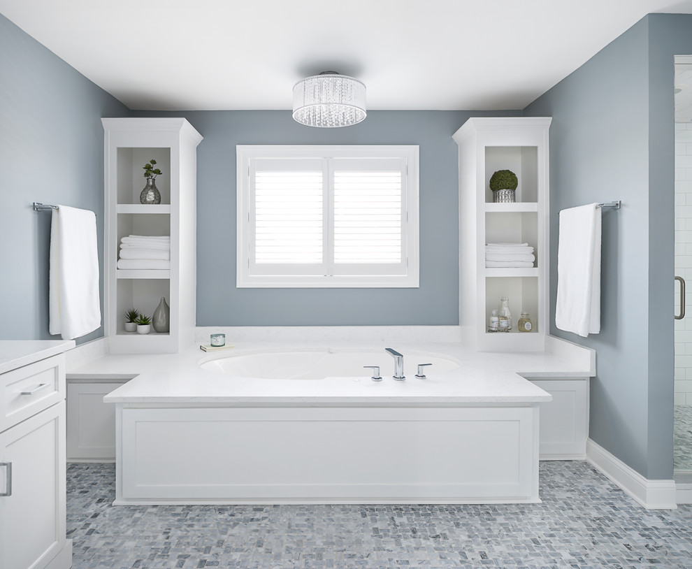 Cette image montre une grande salle de bain principale design avec un placard à porte shaker, des portes de placard blanches, une baignoire encastrée, une douche d'angle, un carrelage blanc, des carreaux de céramique, un mur bleu, un sol en marbre, un lavabo encastré, un plan de toilette en quartz modifié, un sol gris, une cabine de douche à porte battante et un plan de toilette blanc.