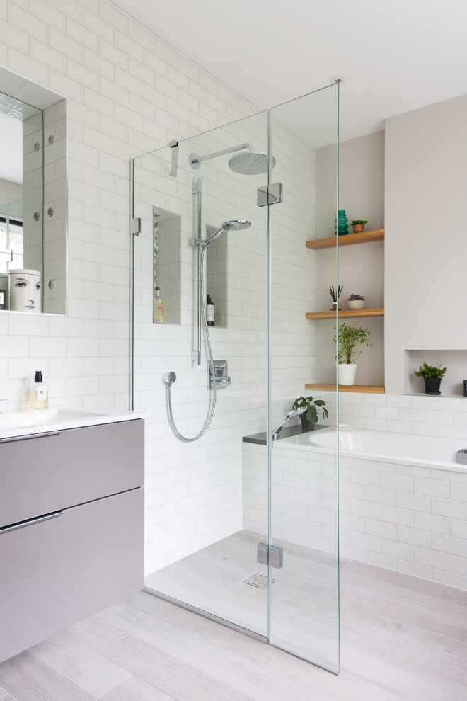 This is an example of a medium sized contemporary wet room bathroom in Other with flat-panel cabinets, grey cabinets, a built-in bath, white tiles, metro tiles, grey walls, laminate floors, a wall-mounted sink, grey floors and an open shower.