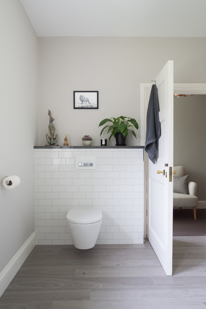 Ejemplo de cuarto de baño actual de tamaño medio con sanitario de pared, baldosas y/o azulejos blancos, baldosas y/o azulejos de cemento, paredes grises, suelo laminado y suelo gris
