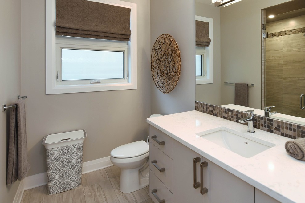 Bild på ett funkis vit vitt badrum, med släta luckor, beige skåp, en toalettstol med separat cisternkåpa, brun kakel, beige väggar, ett integrerad handfat, bänkskiva i kvartsit och beiget golv