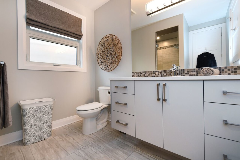 Foto på ett funkis vit badrum, med släta luckor, beige skåp, en toalettstol med separat cisternkåpa, brun kakel, beige väggar, ett integrerad handfat, bänkskiva i kvartsit och beiget golv