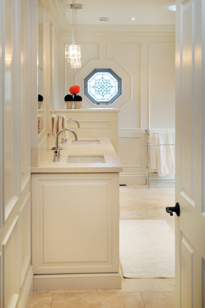 Cette image montre une grande salle de bain principale traditionnelle avec un lavabo encastré, un placard avec porte à panneau encastré et un plan de toilette en marbre.