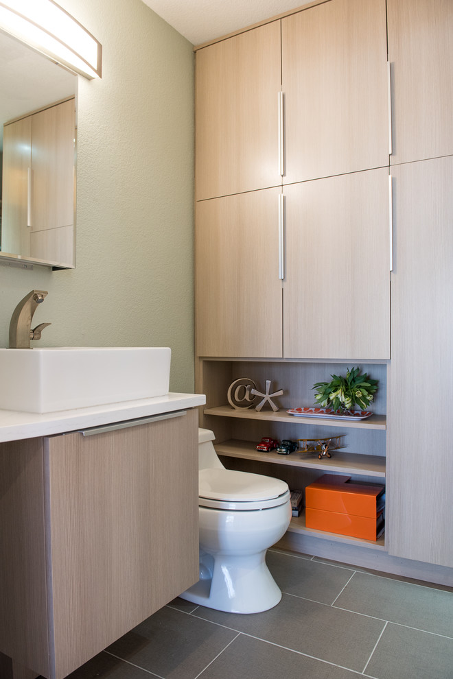 Imagen de cuarto de baño minimalista pequeño con armarios con paneles lisos, puertas de armario de madera clara, suelo de pizarra, aseo y ducha, lavabo con pedestal, encimera de acrílico, sanitario de una pieza, paredes grises y suelo gris
