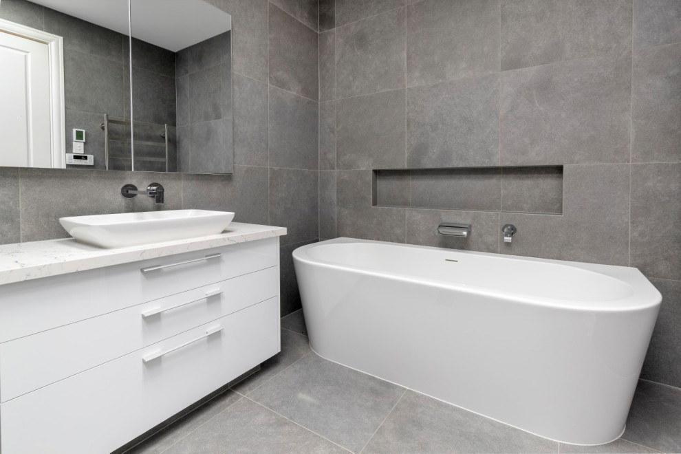 Bathroom - large modern kids' gray tile and porcelain tile porcelain tile and gray floor bathroom idea in Melbourne with flat-panel cabinets, white cabinets, gray walls, a vessel sink, quartz countertops and white countertops