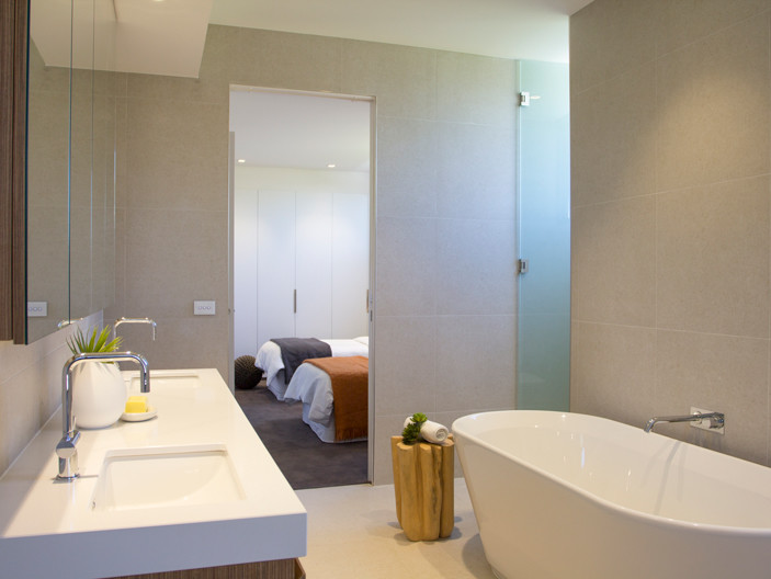 Esempio di una grande stanza da bagno minimalista con ante in legno chiaro, vasca freestanding, doccia alcova, piastrelle in ceramica, lavabo sottopiano, top in quarzo composito e piastrelle grigie