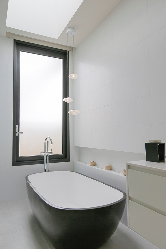 Esempio di una stanza da bagno design con vasca freestanding, pareti bianche, pavimento in gres porcellanato, top in marmo, ante lisce, ante bianche, piastrelle bianche, piastrelle in ceramica e pavimento bianco