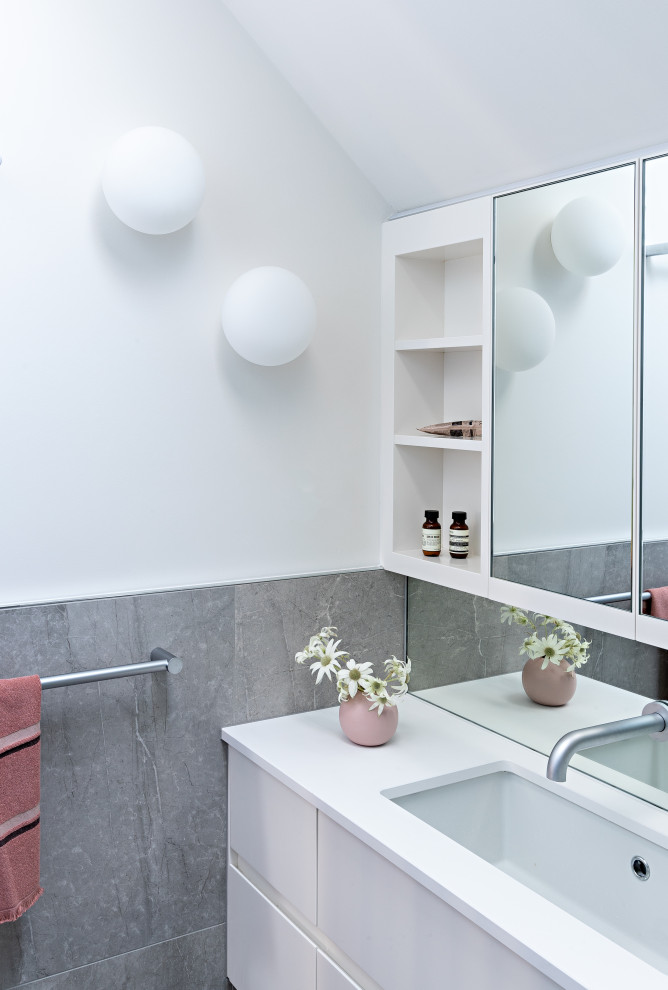 Modernes Badezimmer mit flächenbündigen Schrankfronten, weißen Schränken, weißer Wandfarbe, Unterbauwaschbecken, weißer Waschtischplatte, Einzelwaschbecken, schwebendem Waschtisch und gewölbter Decke in Melbourne