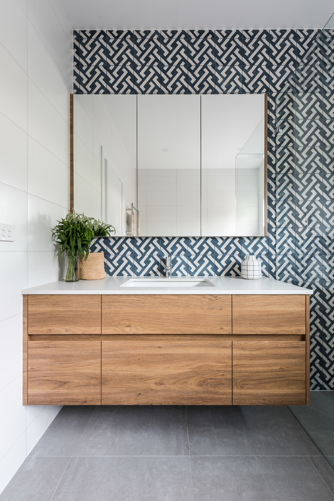 Réalisation d'une salle de bain tradition en bois brun de taille moyenne avec un placard à porte plane, un carrelage bleu, un carrelage blanc, un lavabo encastré et un mur bleu.