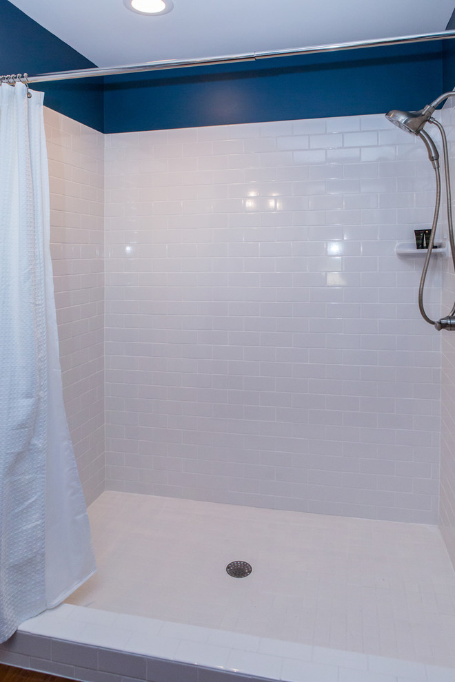 Exemple d'une petite salle de bain moderne en bois foncé avec un placard à porte plane, WC séparés, un carrelage blanc, un carrelage métro, un mur bleu, parquet foncé, un lavabo encastré, un plan de toilette en stratifié, un sol marron et une cabine de douche avec un rideau.