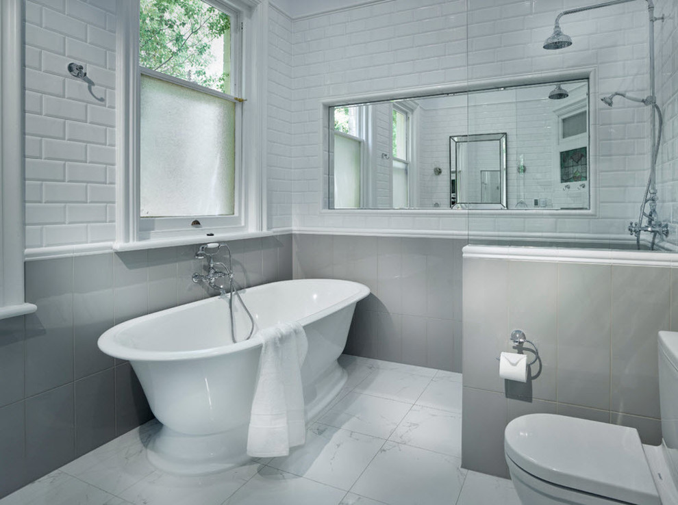 Aménagement d'une salle d'eau classique en bois clair de taille moyenne avec un placard en trompe-l'oeil, une baignoire indépendante, un carrelage gris, des carreaux de céramique, un mur gris, un sol en carrelage de céramique, un lavabo posé et un plan de toilette en marbre.