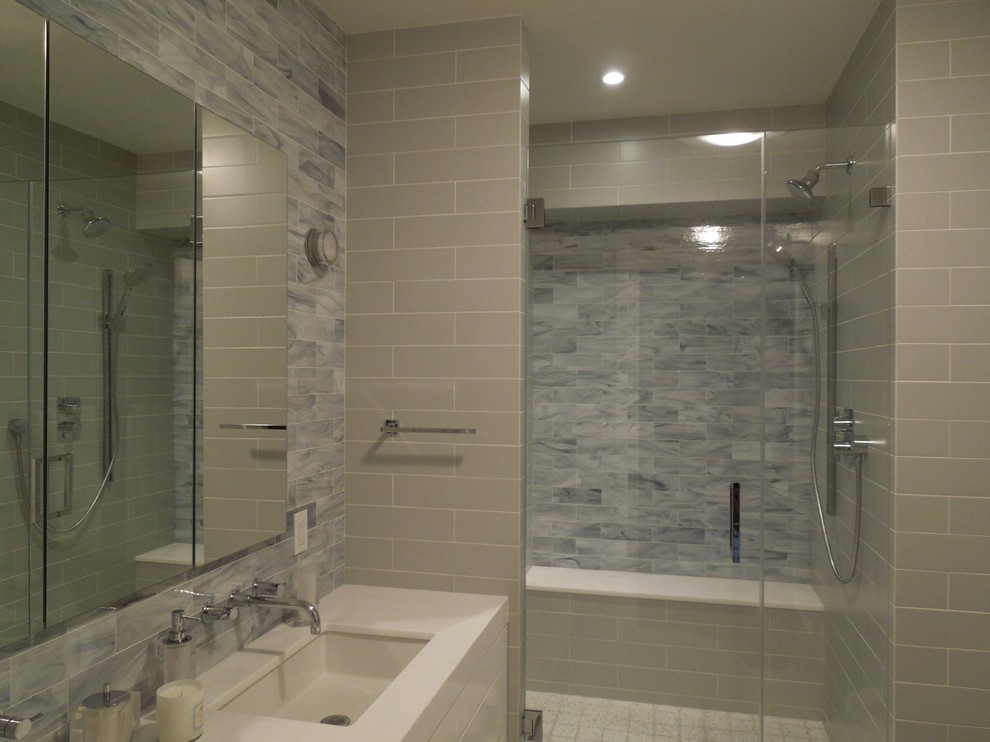 Modernes Duschbad mit integriertem Waschbecken, flächenbündigen Schrankfronten, weißen Schränken, Doppeldusche und grauen Fliesen in New York