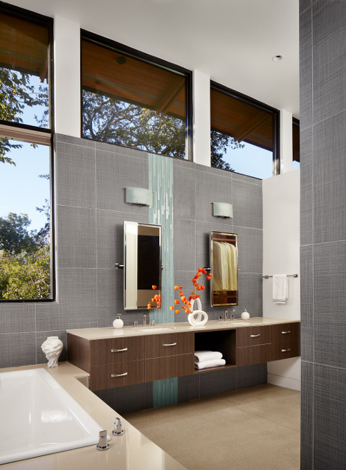 Modelo de cuarto de baño principal moderno con armarios con paneles lisos, puertas de armario de madera oscura, bañera encastrada, baldosas y/o azulejos azules y lavabo integrado