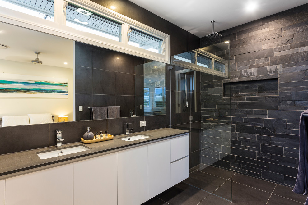 Modern inredning av ett en-suite badrum, med vita skåp, en öppen dusch, svart kakel, svarta väggar och granitbänkskiva