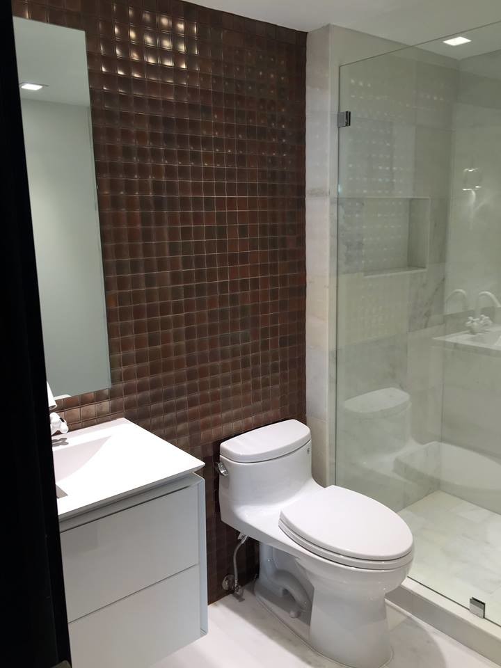Inspiration for a small modern shower room bathroom in Miami with flat-panel cabinets, white cabinets, an alcove shower, a one-piece toilet, white tiles, marble tiles, white walls, marble flooring, an integrated sink, engineered stone worktops, white floors and a hinged door.