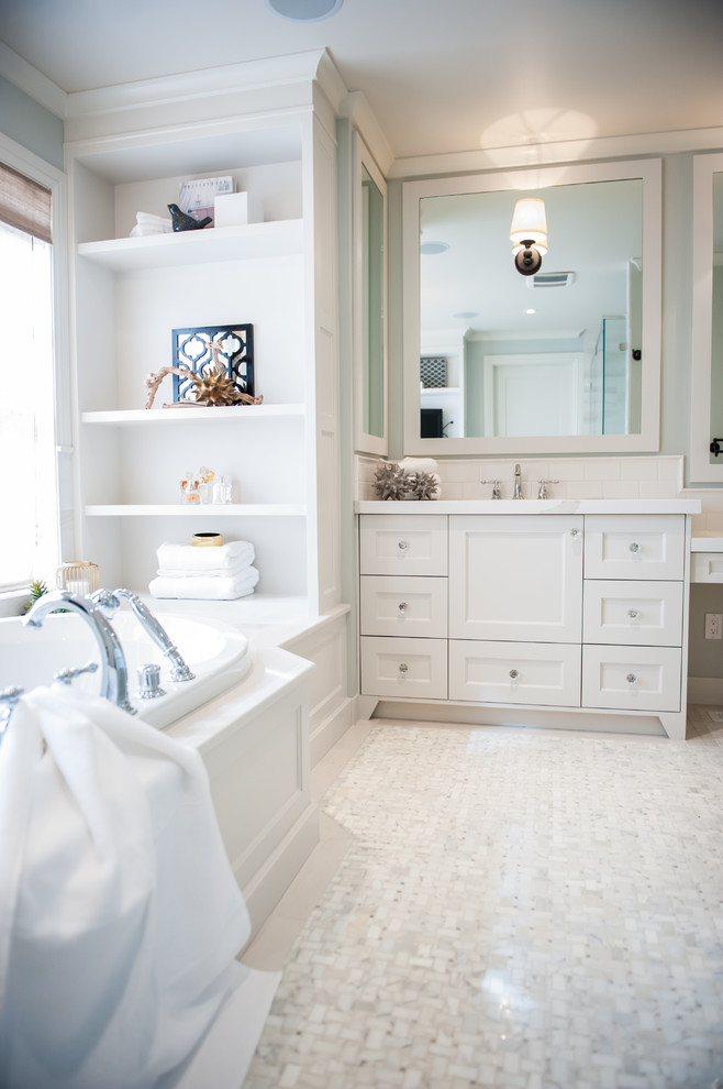Photo of a large traditional ensuite bathroom in Calgary with shaker cabinets, white cabinets, a built-in bath, white tiles, ceramic tiles, grey walls, mosaic tile flooring and a submerged sink.
