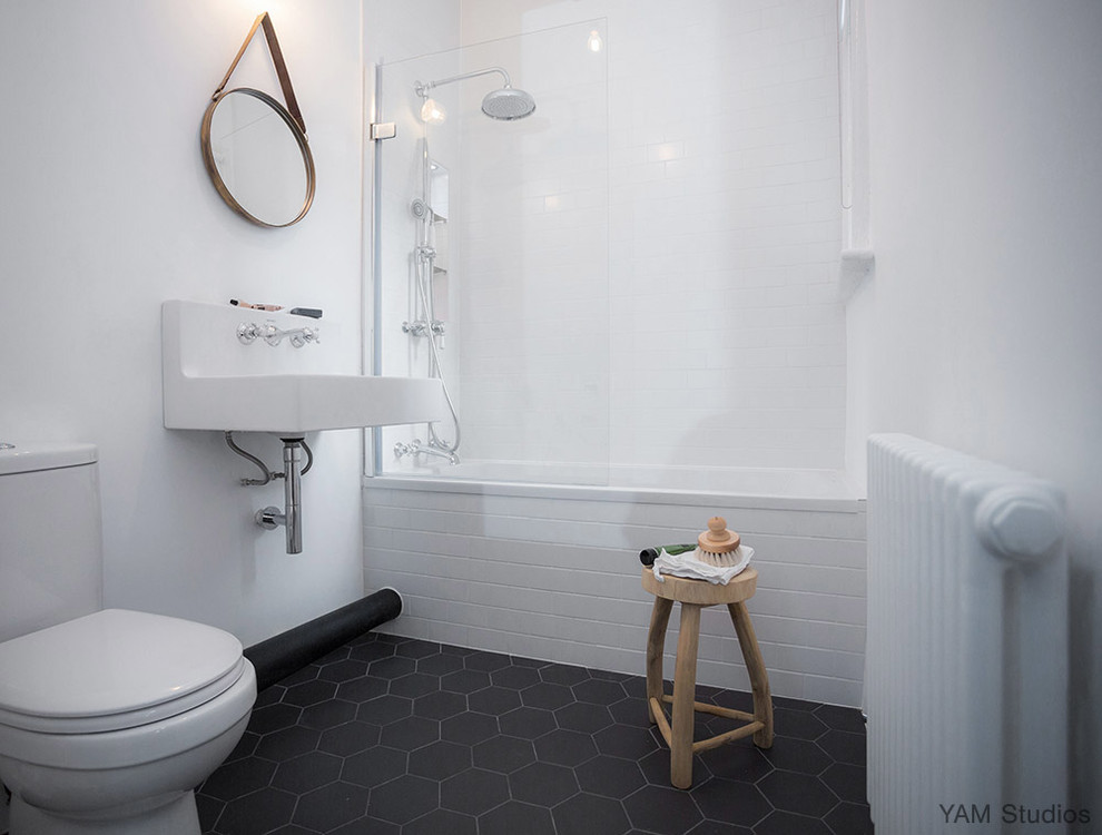 Cette image montre une petite salle d'eau nordique avec une baignoire posée, un combiné douche/baignoire, WC séparés, un carrelage blanc, des carreaux de céramique, un mur blanc, un sol en carrelage de céramique et un lavabo suspendu.