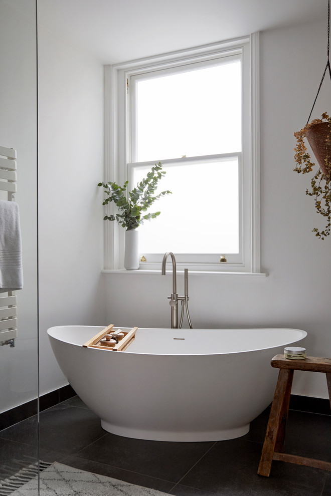 Inredning av ett minimalistiskt stort grå grått en-suite badrum, med ett fristående badkar, en öppen dusch, svart kakel, keramikplattor, vita väggar, cementgolv, ett fristående handfat, marmorbänkskiva, svart golv och med dusch som är öppen