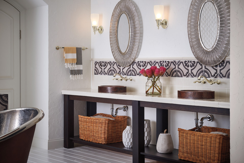 Exemple d'une salle de bain principale nature avec un placard sans porte, une baignoire indépendante, un carrelage multicolore, un carrelage blanc, des carreaux de céramique, une vasque et un plan de toilette en carrelage.