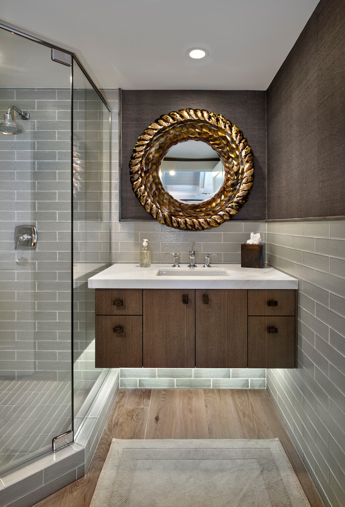 This is an example of a nautical shower room bathroom in Miami with flat-panel cabinets, dark wood cabinets, a corner shower, grey tiles, metro tiles, brown walls, light hardwood flooring, a submerged sink, a hinged door and white worktops.