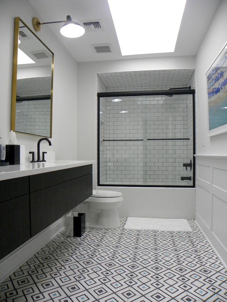На фото: главная ванная комната среднего размера в стиле модернизм с черными фасадами, ванной в нише, белой плиткой, белыми стенами, душем с раздвижными дверями, плоскими фасадами, душем в нише, унитазом-моноблоком, полом из керамической плитки, врезной раковиной, разноцветным полом, белой столешницей, тумбой под одну раковину, подвесной тумбой и панелями на части стены с