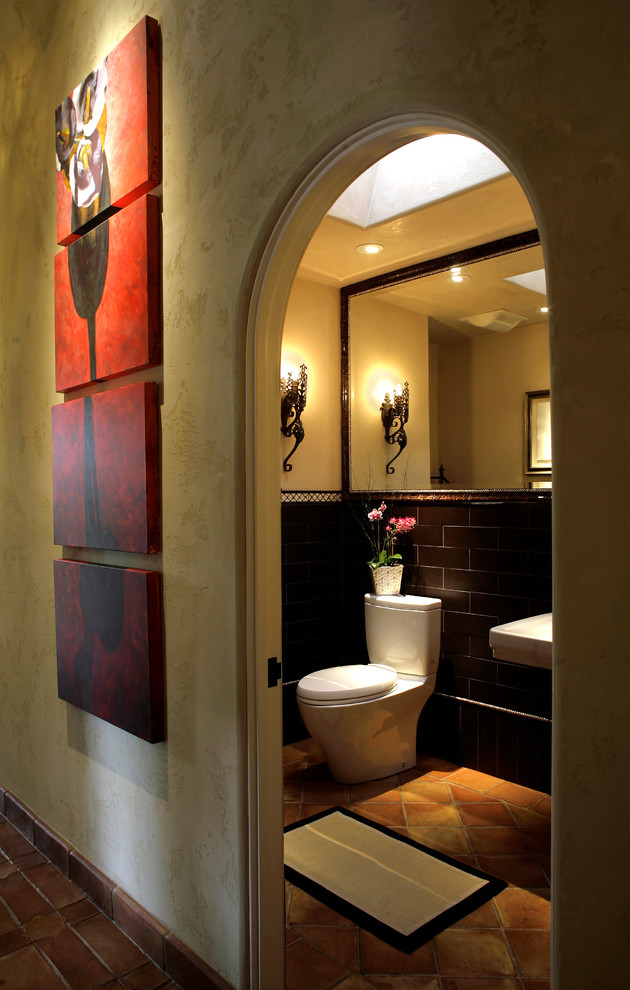Inredning av ett medelhavsstil badrum, med en toalettstol med separat cisternkåpa, brun kakel och klinkergolv i terrakotta