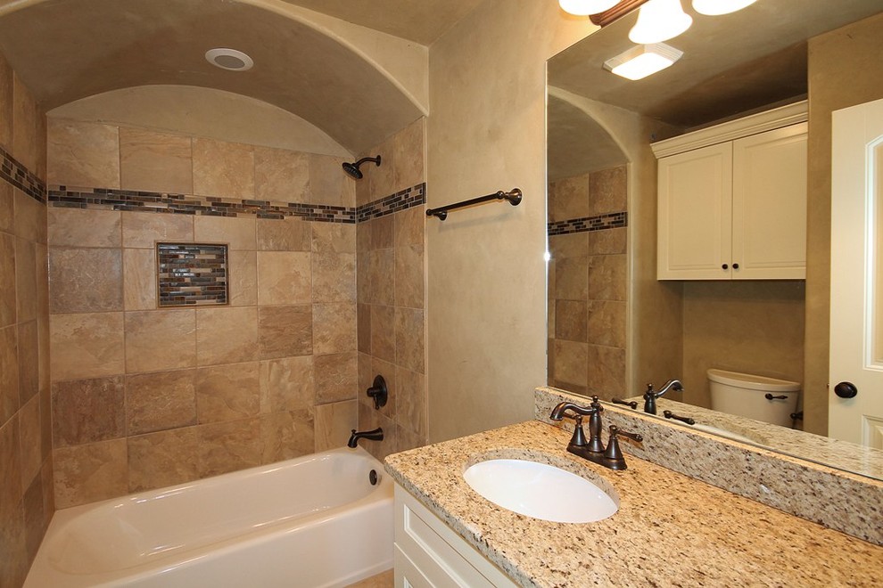Exempel på ett mellanstort klassiskt badrum med dusch, med luckor med infälld panel, vita skåp, ett badkar i en alkov, en dusch/badkar-kombination, en toalettstol med separat cisternkåpa, beige kakel, brun kakel, stickkakel, beige väggar, klinkergolv i keramik, ett undermonterad handfat och granitbänkskiva