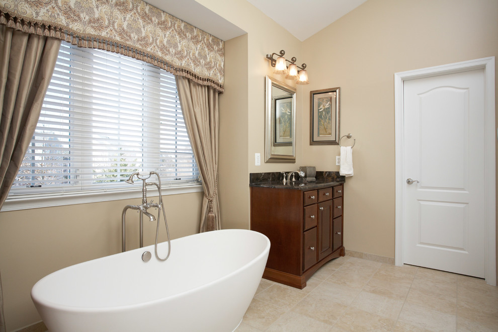 Freestanding bathtub - mid-sized transitional master beige tile and porcelain tile porcelain tile freestanding bathtub idea in DC Metro with raised-panel cabinets, medium tone wood cabinets, marble countertops, beige walls, a two-piece toilet and an undermount sink