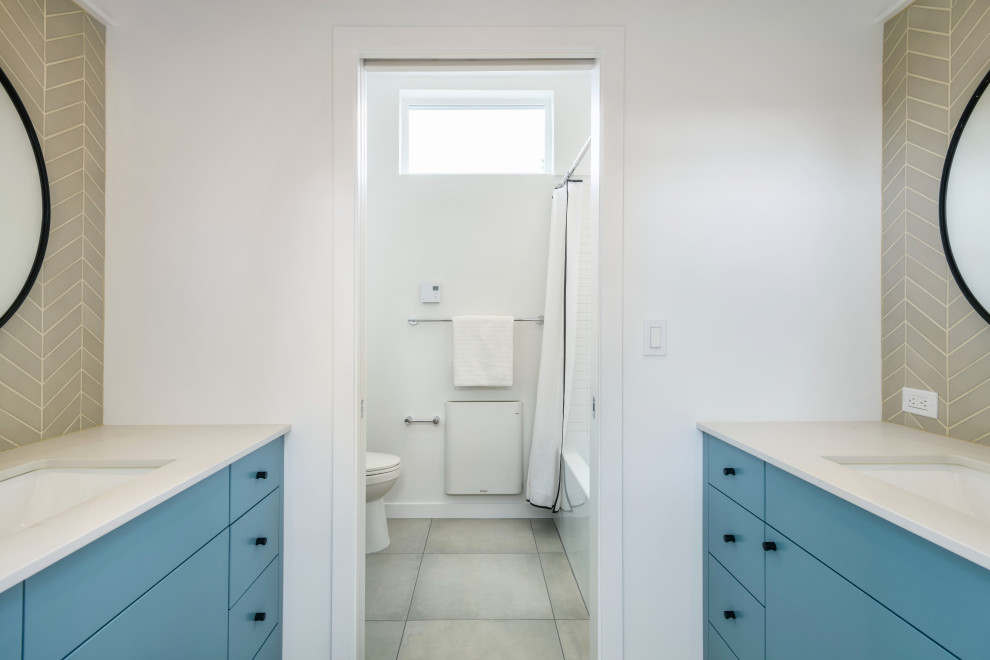 Idéer för att renovera ett mellanstort funkis vit vitt badrum för barn, med släta luckor, blå skåp, ett badkar i en alkov, en toalettstol med hel cisternkåpa, grå kakel, keramikplattor, vita väggar, klinkergolv i porslin, ett undermonterad handfat, bänkskiva i kvarts, grått golv och dusch med duschdraperi