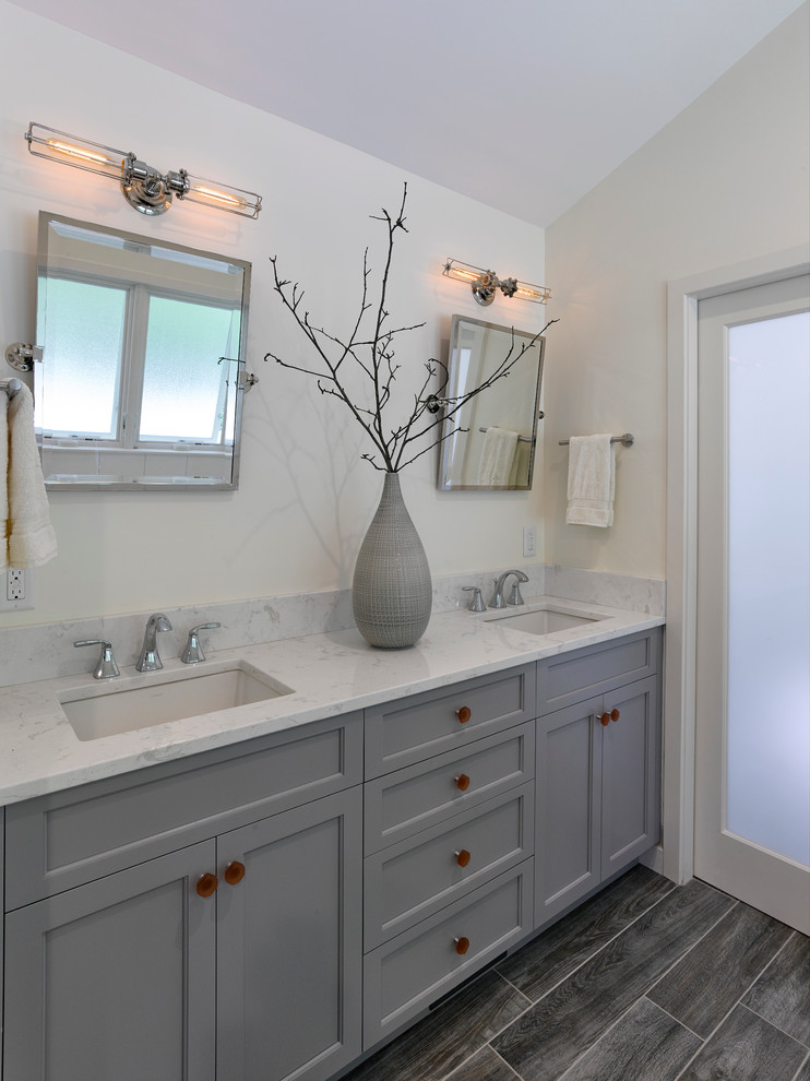 Mid-sized beach style master white tile and porcelain tile ceramic tile doorless shower photo in Baltimore with an undermount sink, recessed-panel cabinets, gray cabinets, quartz countertops, an undermount tub, a two-piece toilet and white walls