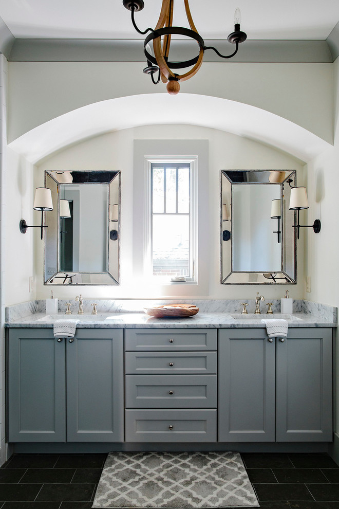 Idée de décoration pour une salle de bain tradition avec un placard avec porte à panneau encastré, des portes de placard grises, un lavabo encastré et un plan de toilette en marbre.
