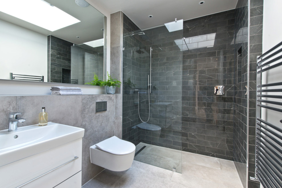Inspiration for a contemporary shower room bathroom in London with flat-panel cabinets, white cabinets, a corner shower, a wall mounted toilet, black tiles, marble tiles, white walls, a console sink, beige floors and an open shower.
