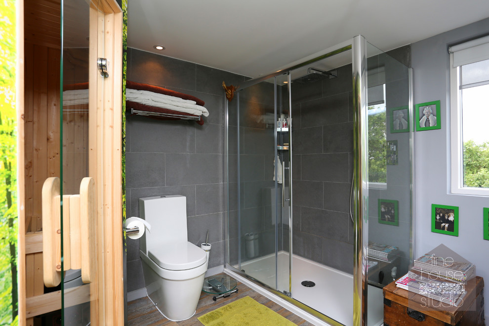 Idee per una grande sauna bohémian con lavabo integrato, consolle stile comò, ante in legno bruno, WC sospeso, piastrelle grigie, piastrelle in pietra, pareti grigie e pavimento in legno massello medio