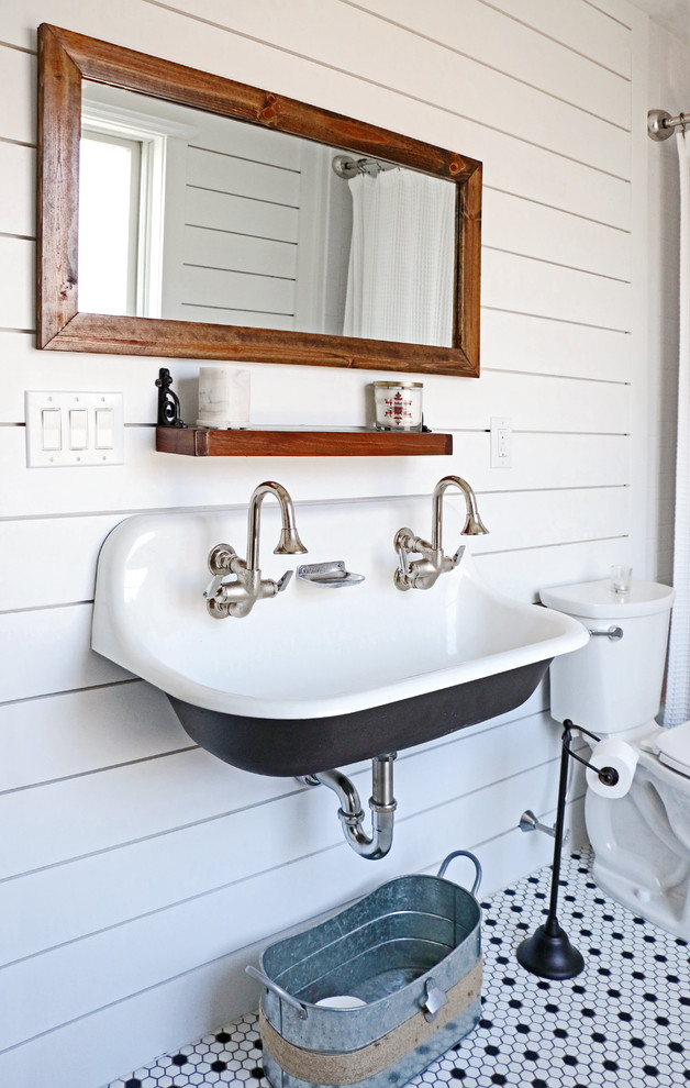This is an example of a medium sized farmhouse family bathroom in Philadelphia with black cabinets, an alcove bath, a shower/bath combination, a two-piece toilet, white tiles, white walls, mosaic tile flooring, a wall-mounted sink, multi-coloured floors, a shower curtain and white worktops.