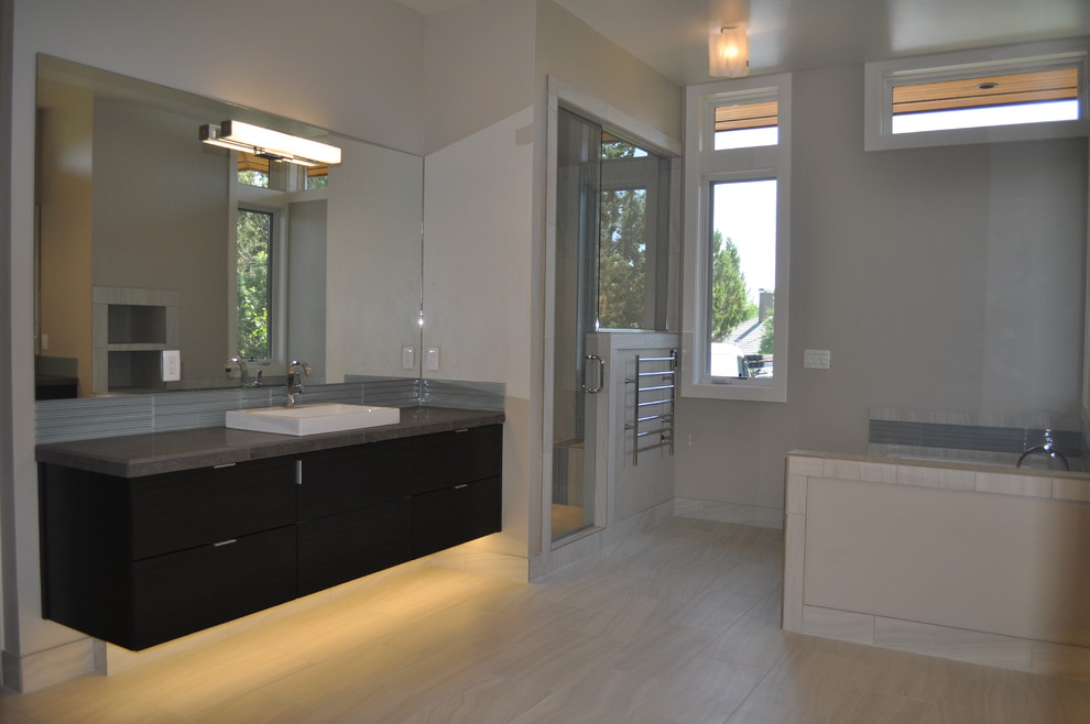 Exemple d'un grand sauna tendance en bois foncé avec une vasque, un placard à porte plane, un plan de toilette en carrelage, une baignoire posée, un carrelage gris, des carreaux de porcelaine, un mur gris et un sol en carrelage de porcelaine.
