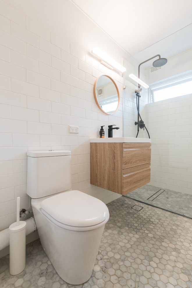 Exempel på ett litet modernt en-suite badrum, med möbel-liknande, skåp i ljust trä, en öppen dusch, en toalettstol med hel cisternkåpa, vit kakel, porslinskakel, vita väggar, klinkergolv i keramik, ett väggmonterat handfat, marmorbänkskiva, grått golv och med dusch som är öppen