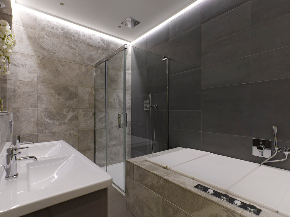 На фото: ванная комната в современном стиле с монолитной раковиной, угловым душем и серой плиткой с