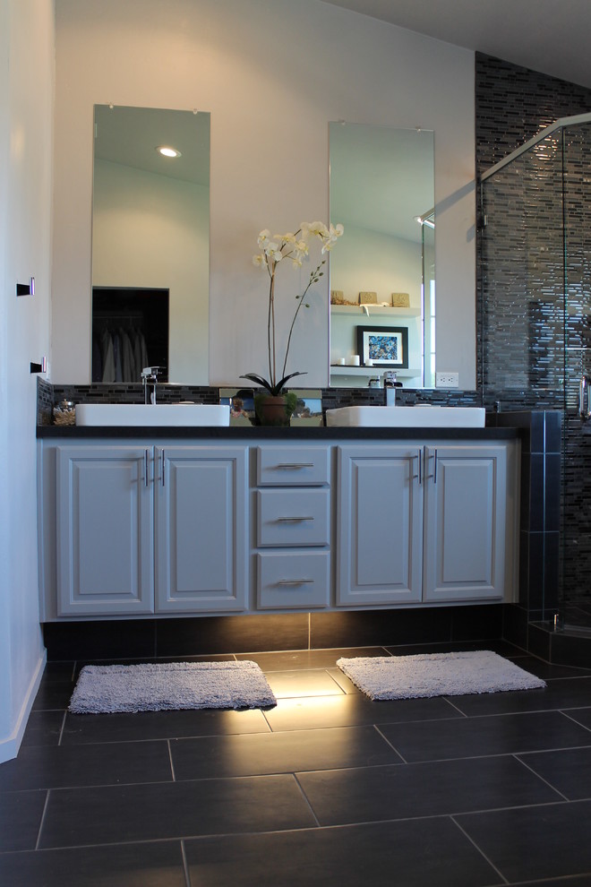 Modern inredning av ett badrum, med ett fristående handfat, luckor med upphöjd panel, grå skåp, bänkskiva i kvarts, ett hörnbadkar, en hörndusch och grå kakel