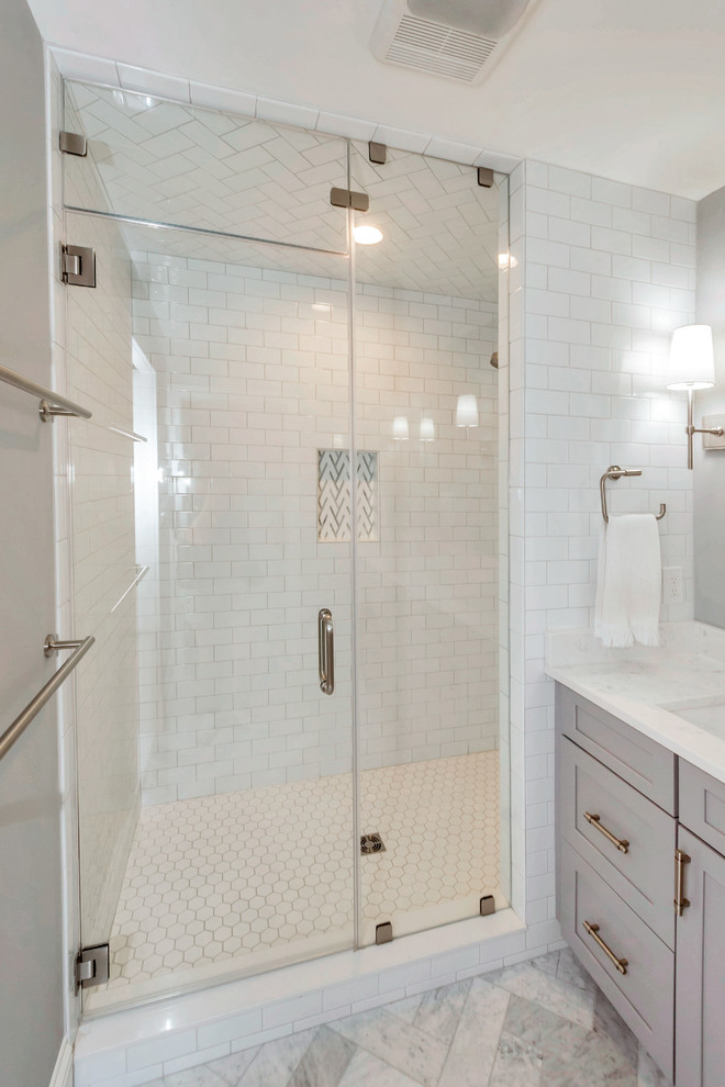 На фото: главная ванная комната среднего размера в стиле неоклассика (современная классика) с фасадами в стиле шейкер, серыми фасадами, ванной в нише, душем в нише, белой плиткой, плиткой кабанчик, серыми стенами, мраморным полом, врезной раковиной, столешницей из искусственного кварца, серым полом, душем с распашными дверями и белой столешницей с