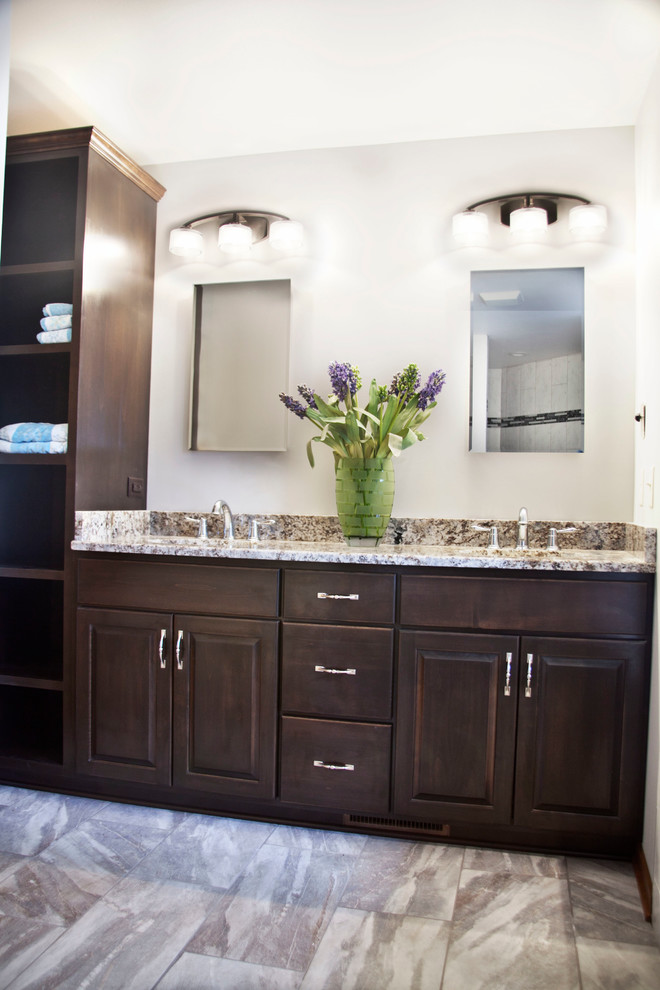 Exemple d'une salle de bain principale tendance en bois foncé de taille moyenne avec un placard avec porte à panneau surélevé, un mur blanc, un sol en carrelage de céramique, un lavabo encastré, un plan de toilette en granite et un sol gris.
