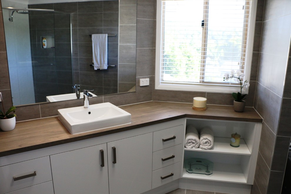 На фото: большая ванная комната в современном стиле с серой плиткой и столешницей из ламината с
