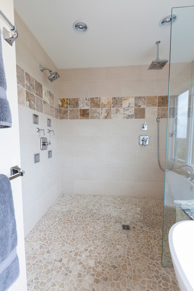 Photo of a large contemporary ensuite bathroom in New York with raised-panel cabinets, brown cabinets, a freestanding bath, a built-in shower, a two-piece toilet, beige tiles, porcelain tiles, yellow walls, pebble tile flooring, a vessel sink, onyx worktops, grey floors and an open shower.
