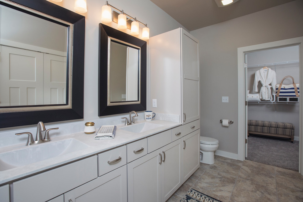 Imagen de cuarto de baño principal de estilo americano de tamaño medio con armarios estilo shaker, puertas de armario blancas, suelo de baldosas de cerámica, lavabo integrado, encimera de acrílico y suelo marrón