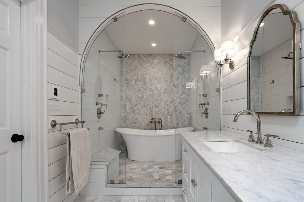 Idéer för att renovera ett stort lantligt vit vitt en-suite badrum, med luckor med infälld panel, vita skåp, ett fristående badkar, en dusch i en alkov, grå kakel, vit kakel, marmorkakel, vita väggar, marmorgolv, ett undermonterad handfat, marmorbänkskiva, grått golv och dusch med gångjärnsdörr